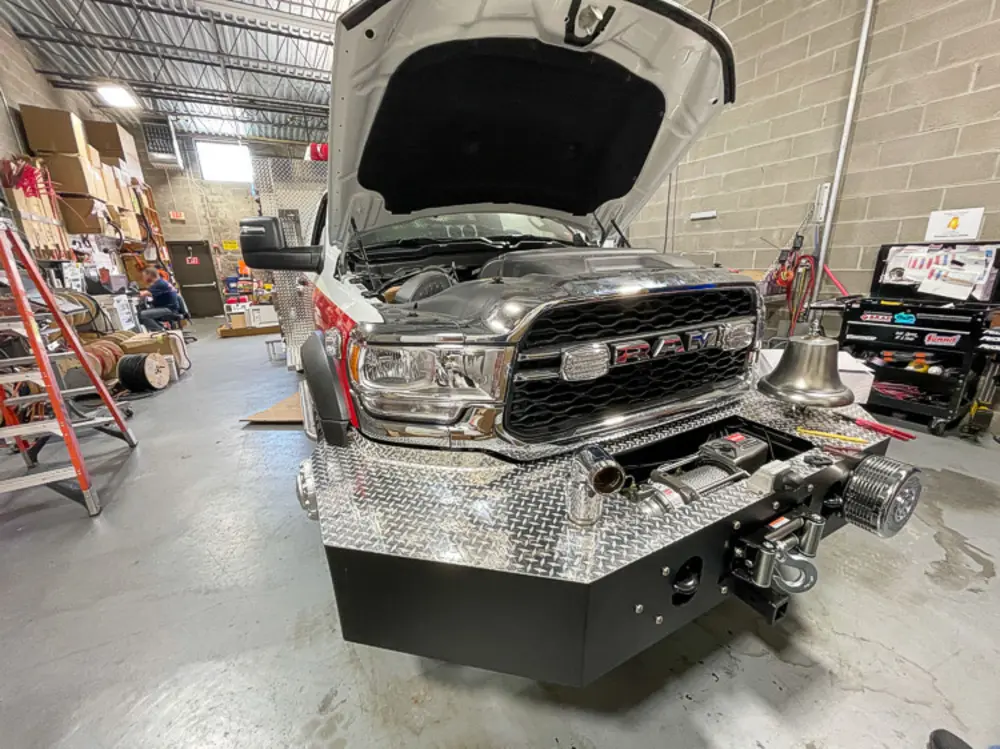 Exterior view of small fire truck showing cab, body compartments, and wheel/tire area.